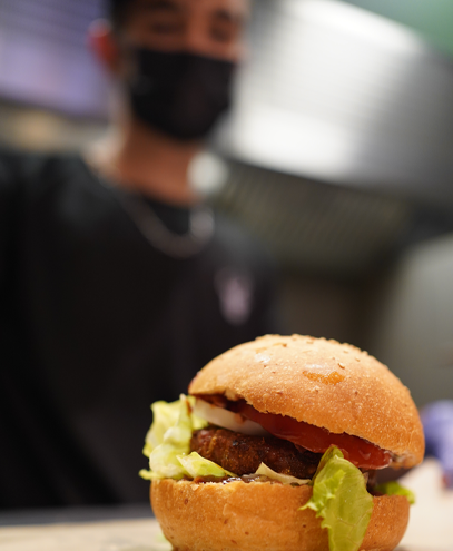 Burger avec un employé du restaurant flou en arrière-plan, photo par l'agence de communication Glick